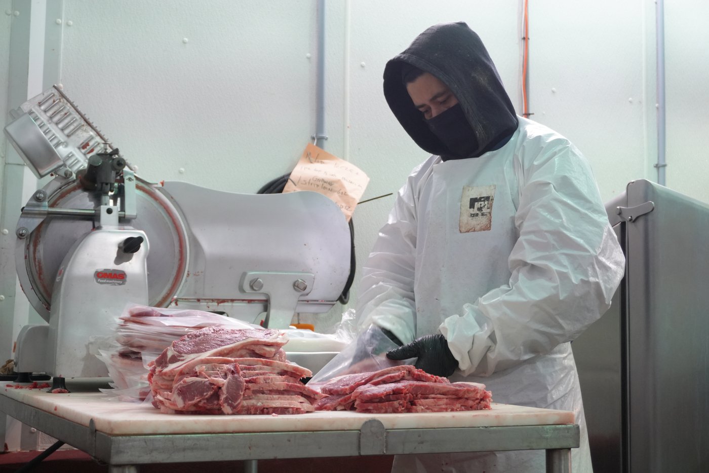 A Venerica butcher preparing custom cuts with meat-cutting equipment